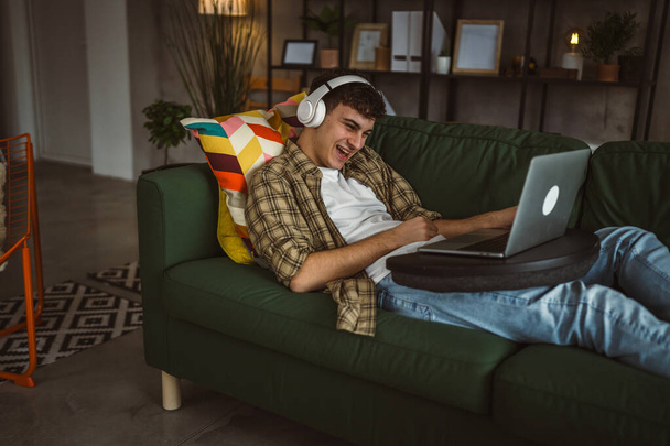Ένας καυκάσιος έφηβος άντρας χρησιμοποιεί φορητό υπολογιστή έχει βιντεοκλήση στο σπίτι - Φωτογραφία, εικόνα