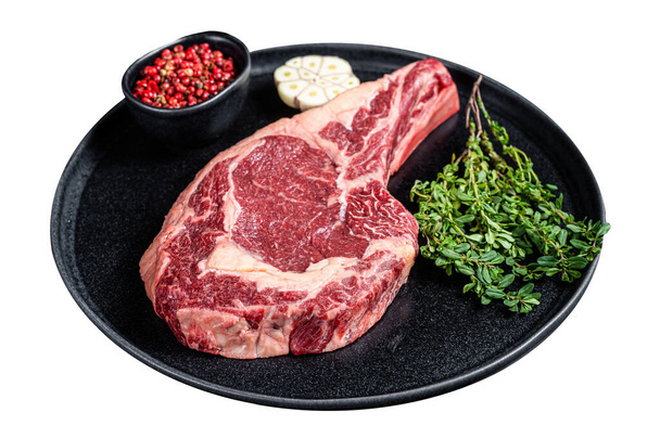 Trockenes gealtertes Cowboy- oder Rib-Eye-Steak, rohes Rindfleisch mit Kräutern. Vereinzelt auf weißem Hintergrund. Ansicht von oben - Foto, Bild