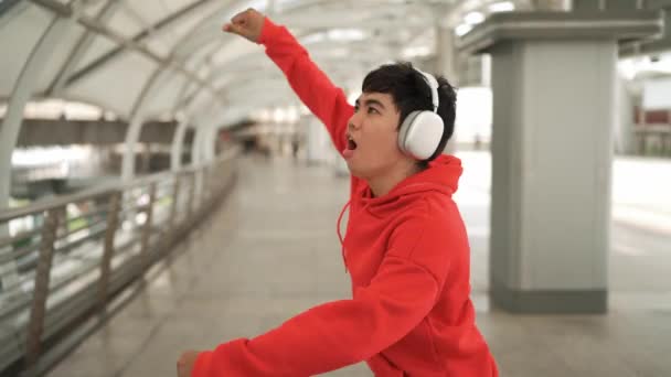 Dancer listen to hip hop music while sing along and walking at corridor. Handsome hipster wearing stylish cloth and headphone express feeling of lively or happy mood. Outdoor sport 2024. Sprightly. - Footage, Video