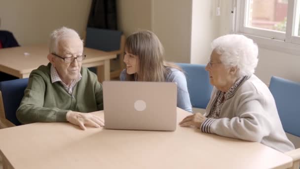 Vídeo en cámara lenta de una nieta ayudando a sus abuelos a usar el portátil en geriátrico - Metraje, vídeo
