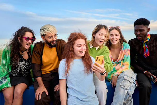 Bir grup genç arkadaş dışarıda cep telefonu kullanıyor ve komik bir şey izliyorlar. Teknolojiye bağımlı bin yıllık toplum kavramı. Sosyal Medya İletişim Üretimi Z - Fotoğraf, Görsel