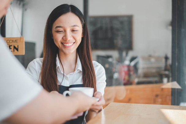 Amigável barista servindo café com um sorriso quente para um cliente em um ambiente acolhedor e convidativo café. - Foto, Imagem