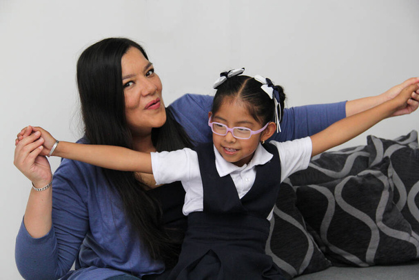 Gescheiden alleenstaande Latijnse moeder en brunette 4-jarige dochter in uniform en bril praten en spelen na school - Foto, afbeelding