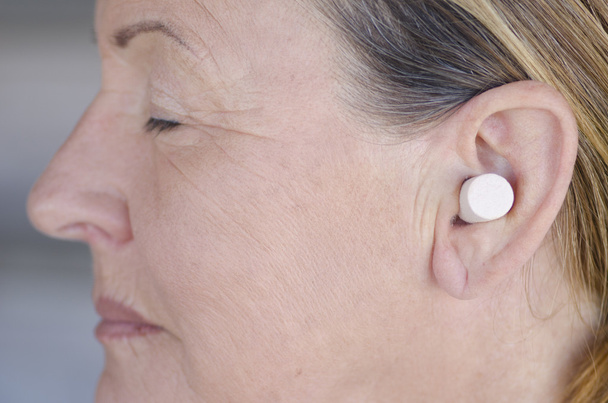 Woman blocking sound with ear plug closed eyes - Foto, afbeelding