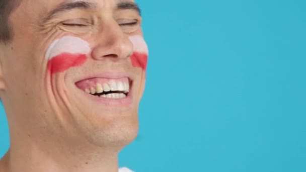 Video im Atelier mit dem Chroma eines glücklichen Mannes mit aufgemalter polnischer Fahne im Gesicht, der in den leeren Kopierraum blickt. Nahaufnahme - Filmmaterial, Video