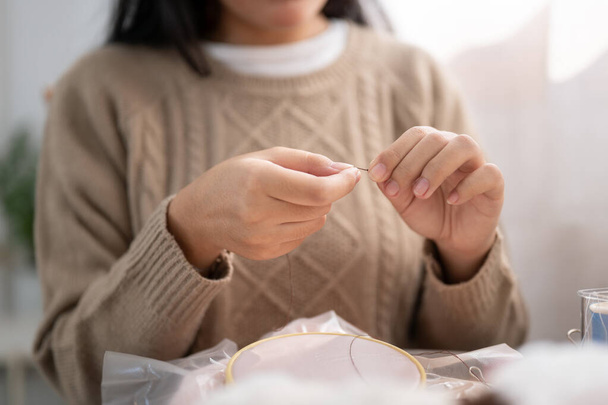 A close-up image of a woman inserting a needle, threading a sewing needle, sewing at home. embroidery, tailor, needlework - Photo, Image