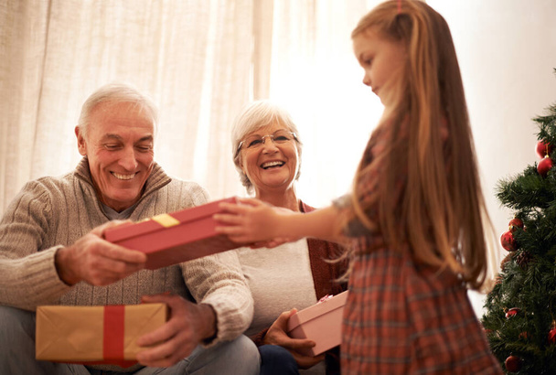 Család, karácsonyi ajándékozás és ajándékok gyerekekkel és nagyszülőkkel, valamint fa a nappaliban. Otthon, boldog és jelen ünnep és ünneplés egy párt szeretettel, gondossággal és kötődés mosollyal. - Fotó, kép