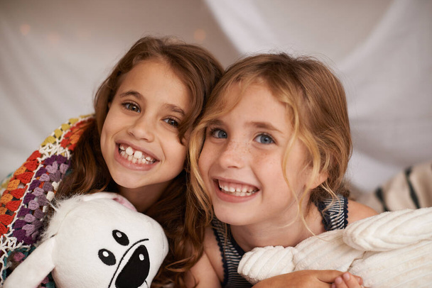 Feliz, brinquedos e retrato de crianças no quarto para brincar, ligação e animado para a festa do pijama em casa. Noite, amigos e meninas na cama em tenda ou cobertor forte para a infância, diversão e felicidade. - Foto, Imagem