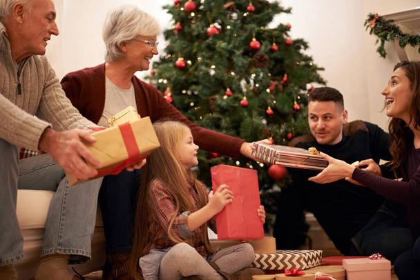 Οικογένεια, παρόν και Χριστούγεννα στο σπίτι με αγάπη, δίνοντας και φροντίζοντας μαζί σε εορταστική εκδήλωση. Ευτυχία, χαμόγελο και δέντρο με γιορτή, παιδί και γάμο σε ένα σπίτι με παππούδες και γιαγιάδες και γιορτινό δώρο. - Φωτογραφία, εικόνα