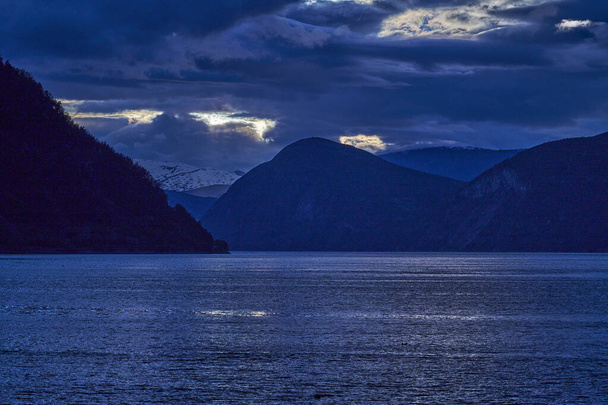 zonsondergang in het prachtige Sognefjord in Noorwegen, met rimpelingen in het water en een dramatische hemel. - Foto, afbeelding