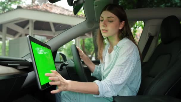Vakantie vakantie road trip met milieuvriendelijke auto concept. Eco-bewuste jonge paar op de bestuurdersstoel houden lege copyspace groene scherm auto 's monitor voor EV batterij status. Hoog - Video