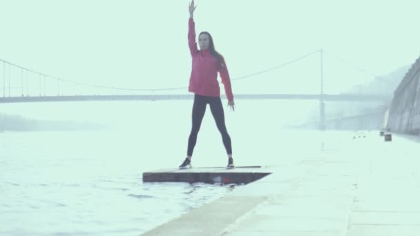 Mladá žena cvičí venku na břehu řeky. Sportovní dívka ve městě - Záběry, video