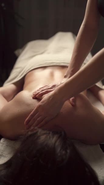 Masseur masseren rug-en schouderbladen van een volwassen vrouw liggend op massagetafel. Massage spa behandelingen concept. Verticale video - Video