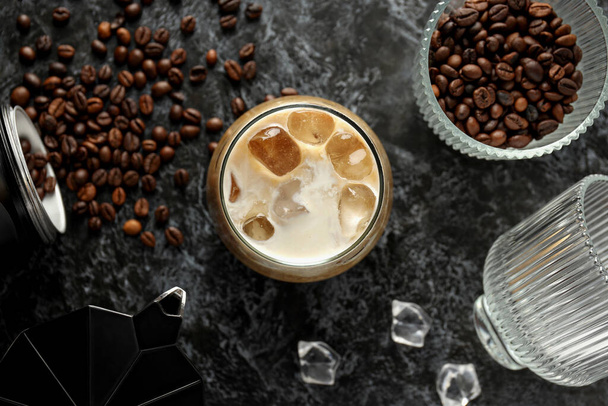 Glass with iced coffee drink, coffee maker and coffee bean on gray background, top view - Photo, Image