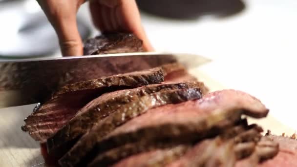 Cook cuts juicy roast beef into thin slices on a cutting board. High quality 4k footage - Felvétel, videó