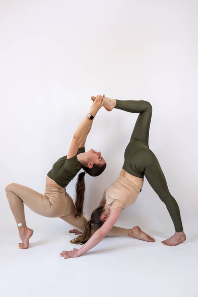 zwei athletische kaukasische Frauen in Sportbekleidung, die zusammen Fitness-Yoga oder Pilates-Übungen vereinzelt machen. Teamwork-Sport für alle als Lebensstil - Foto, Bild
