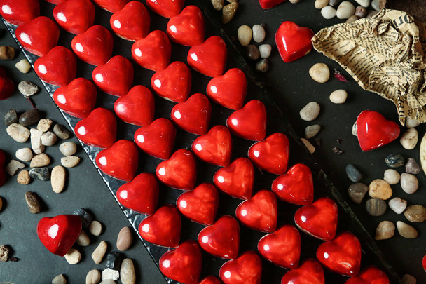 Ένα τραπέζι καλυμμένο με άφθονη ζωηρή κόκκινη διακόσμηση της καρδιάς. - Φωτογραφία, εικόνα