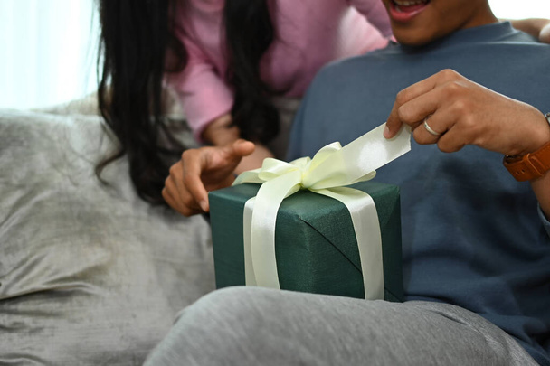 Šťastný muž otevírá dárkovou krabici od své přítelkyně. Lidé, oslavy a prázdniny koncept. - Fotografie, Obrázek