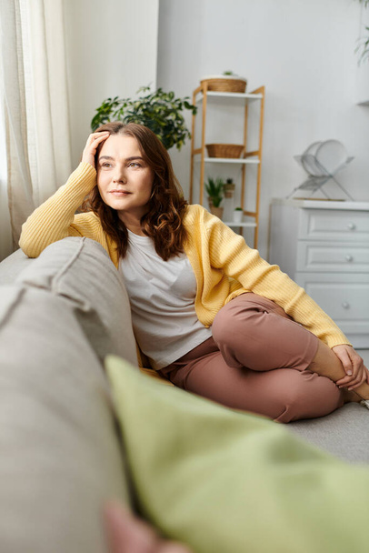 Middle-aged woman peacefully relaxes on couch in cozy living room - Photo, Image