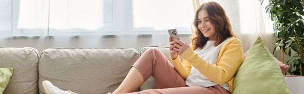 Middle-aged woman on couch engrossed in cellphone. - Photo, Image