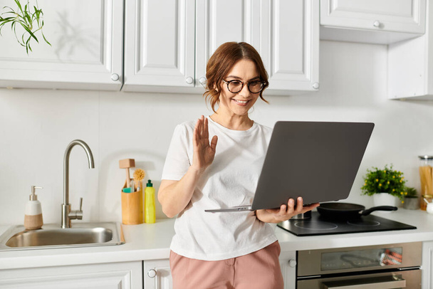 Middle-aged woman standing in front of laptop - Photo, Image