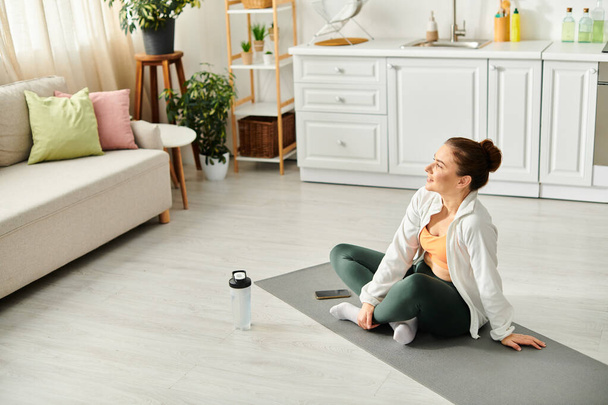 Eine Frau mittleren Alters findet Frieden, während sie in ihrem Wohnzimmer auf einer Yogamatte sitzt. - Foto, Bild