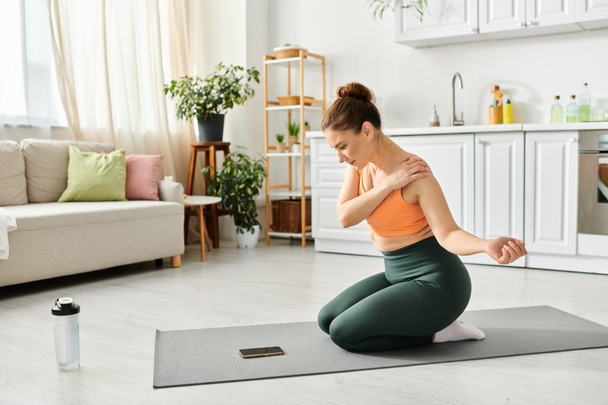 Femme d'âge moyen exercices sur un tapis de yoga dans un salon confortable. - Photo, image