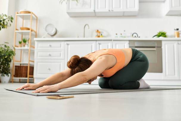 Женщина средних лет изящно выполняет позу йоги на полу дома. - Фото, изображение