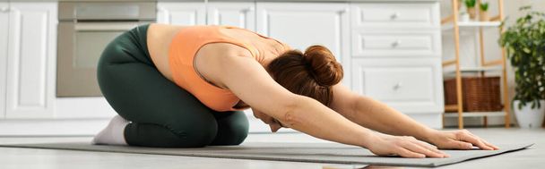 Mujer de mediana edad con elegancia sostiene una pose de yoga en una esterilla. - Foto, Imagen