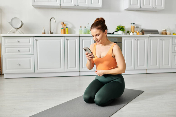 Mujer de mediana edad en la esterilla de yoga comprobar el teléfono inteligente. - Foto, Imagen