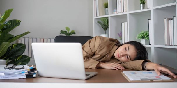 Азіатська бізнес-леді відчуває себе втомленою і напруженою через невдалий бізнес під час роботи в домашньому офісі, прикрашеному заспокійливими зеленими рослинами.. - Фото, зображення