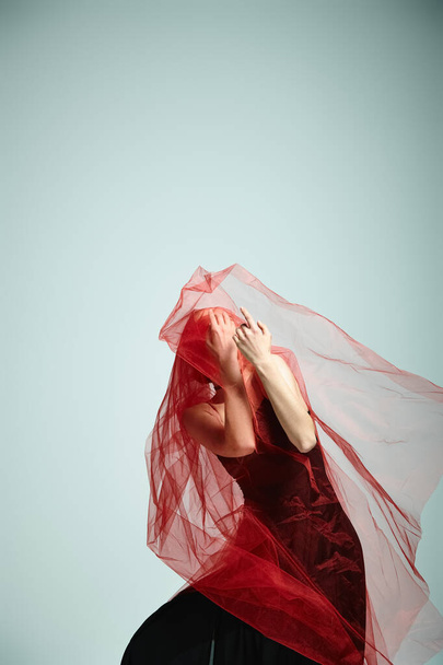 Jovem bailarina em um vestido preto dança graciosamente com um véu na cabeça. - Foto, Imagem