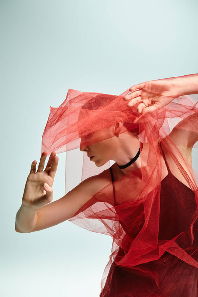 Una joven bailarina con un vestido negro se mueve elegantemente con un velo sobre su cabeza. - Foto, Imagen