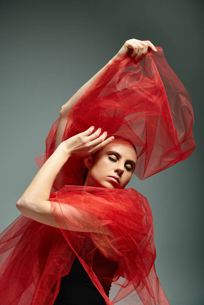 A young beautiful ballerina in a red shawl dances gracefully. - Photo, Image