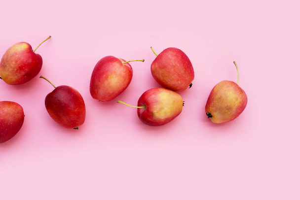 Manzanas rojas pequeñas frescas sobre fondo rosa - Foto, Imagen