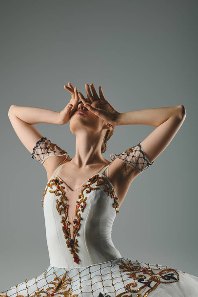 Beyaz ve altın elbiseli genç, güzel bir balerin zarif ve tutkulu bir şekilde dans ediyor.. - Fotoğraf, Görsel