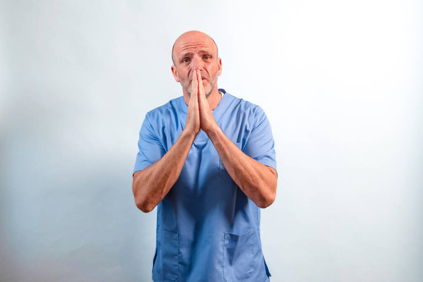 Ritratto di fisioterapista in abito azzurro e mani unite supplicando. - Foto, immagini