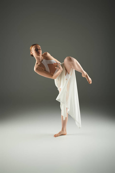 Beyaz elbiseli genç balerin zarafet ve zarafetle ayakta duruyor.. - Fotoğraf, Görsel