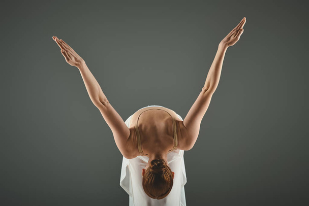 Een jonge, mooie ballerina met haar handen elegant omhoog in de lucht. - Foto, afbeelding