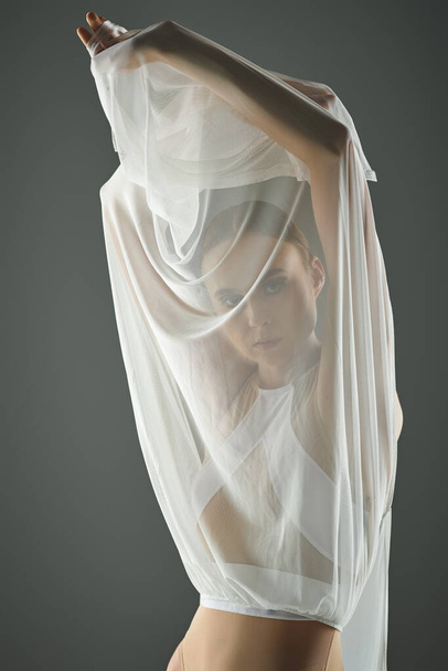 Egy fiatal, gyönyörű balerina, tiszta fehér ruhában, fátyollal, kecsesen táncol.. - Fotó, kép