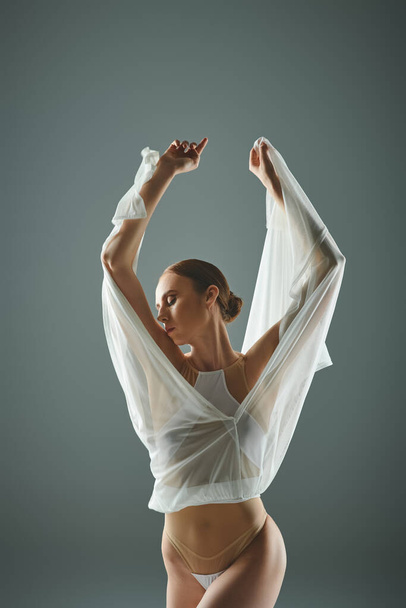 Νεαρή όμορφη μπαλαρίνα σε λευκό πουκάμισο αναδεικνύει το ταλέντο της στο χορό. - Φωτογραφία, εικόνα