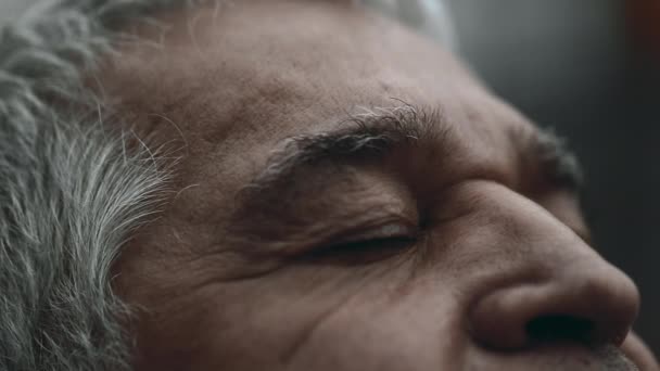 Contemplatieve senior man sluit de ogen in bedachtzame expressie, opent de ogen en staart naar UPWARDS in pensieve spirituele blik - Video