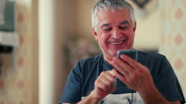 Пожилой мужчина, читающий воодушевляющее сообщение по мобильному телефону, крупным планом седовласого белого мужчины 70-х годов, положительно кивает, глядя на экран смартфона - Кадры, видео