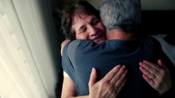 Couple âgé heureux embrasser affectueux, conjoint aîné avec bras autour du mari dans le moment tendre attentionné debout par la fenêtre à la maison résidentielle - Séquence, vidéo