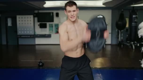 Fiatal atlétikai férfi edz és gyakorol vas súlyzó palacsinta a modern tornateremben. Sportos srác edzés sporteszközökkel - Felvétel, videó