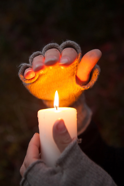 junge Frau blickt auf eine Kerze und betet Hände mit Kerze im dunklen Hintergrund - Foto, Bild