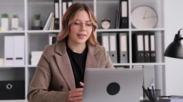 Profesjonalna, kaukaska bizneswoman rozmawiająca przez telefon wideo za pomocą laptopa, pracująca w biurze. Zaangażowany w konferencję internetową, spotkanie lub rozmowę o pracę. - Materiał filmowy, wideo