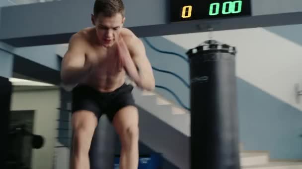 Νεαρός αθλητής με μυϊκό σώμα που γυμνάζεται στο γυμναστήριο. Αθλητικός άντρας κάνει λειτουργική εκπαίδευση και πηδάει στο κουτί. Αθλητισμός και ενεργός τρόπος ζωής - Πλάνα, βίντεο