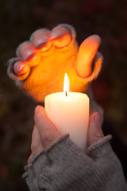 Молода жінка, дивлячись на свічку руки молитися зі свічкою в темному тлі - Фото, зображення