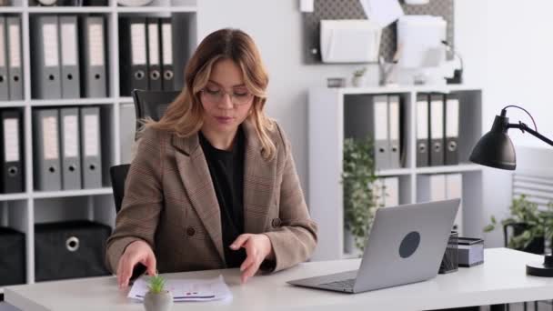 Cheerful Caucasian woman working with documents and talking on video call using laptop in office. Online meeting, training, briefing, consultation. - Footage, Video